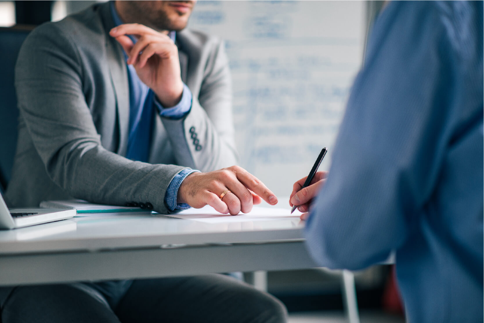 Low angle image two men formal wear sitting desk signing agreement
